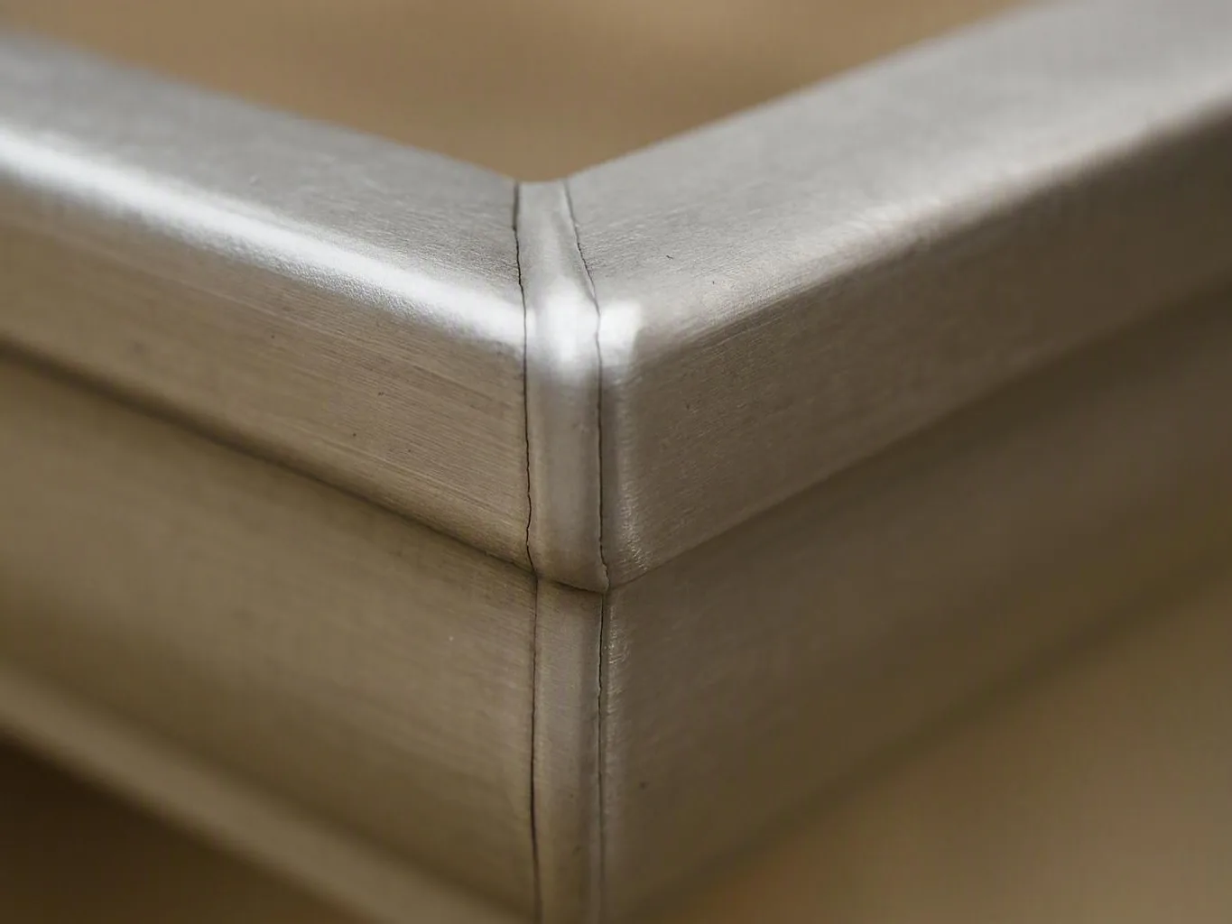 Close-up of a brushed metal gutter corner showing a clean seam and soft reflections
