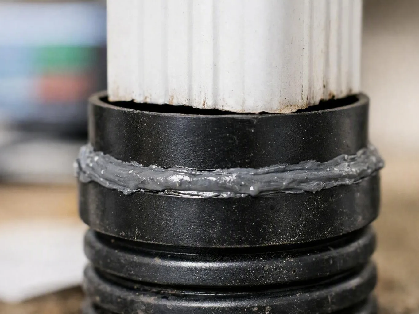 Close-up of a white pole mounted in a black base with gray sealant around the